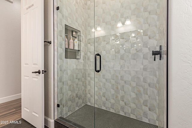 bathroom with wood-type flooring and a shower with door