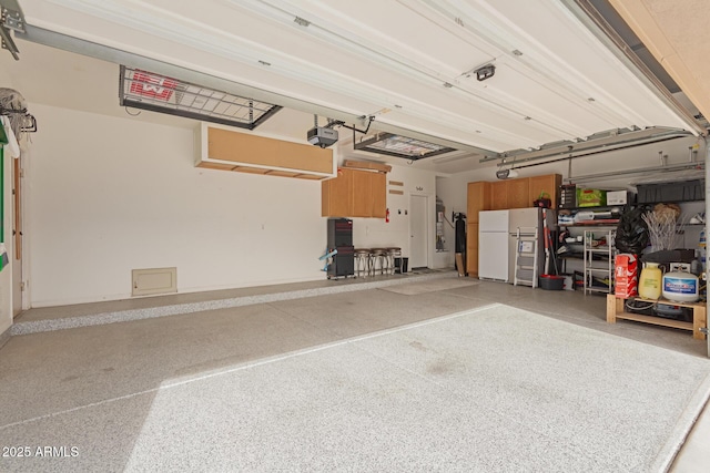 garage with white refrigerator and a garage door opener