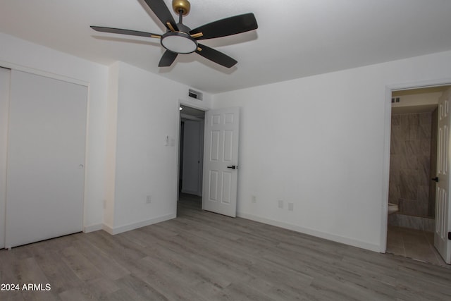 unfurnished bedroom with a closet, ensuite bath, ceiling fan, and light hardwood / wood-style flooring