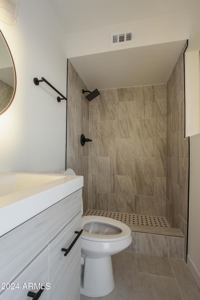 bathroom featuring tile patterned floors, vanity, toilet, and a tile shower