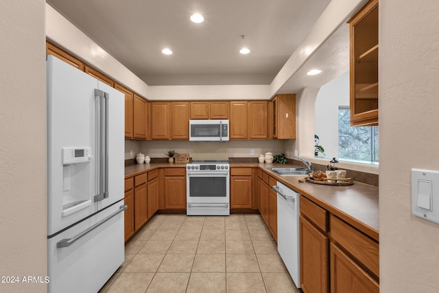 kitchen featuring white appliances, sink, and light tile patterned floors