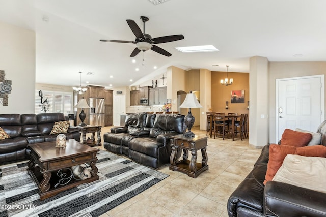 living room with ceiling fan with notable chandelier, lofted ceiling with skylight, and light tile patterned flooring