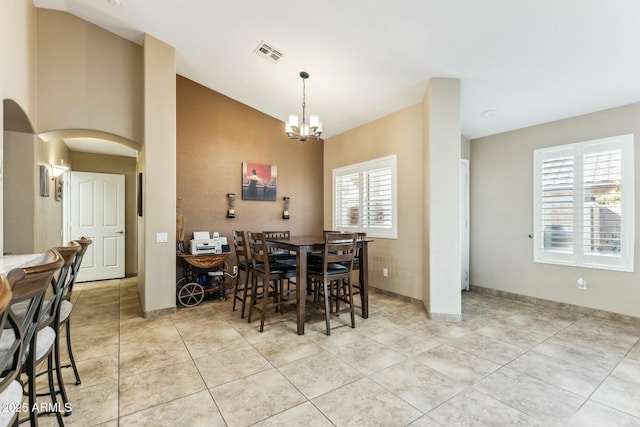 tiled dining area with lofted ceiling and an inviting chandelier