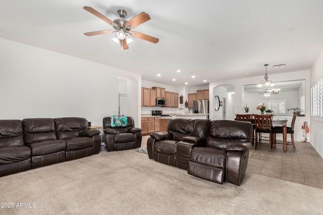 living room featuring ceiling fan with notable chandelier and light colored carpet