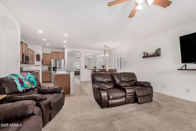 tiled living room featuring sink and ceiling fan with notable chandelier