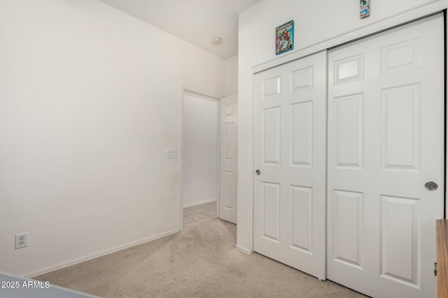 unfurnished bedroom with light colored carpet and a closet