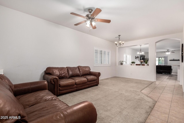 carpeted living room featuring ceiling fan with notable chandelier