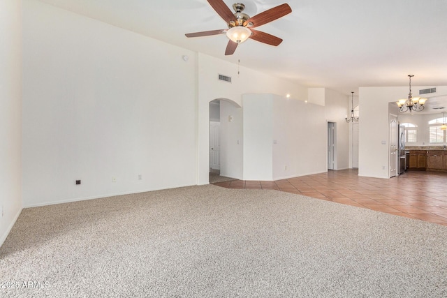 unfurnished living room featuring lofted ceiling, ceiling fan with notable chandelier, and light carpet