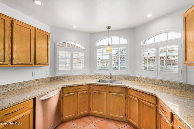 kitchen with light tile patterned flooring, pendant lighting, dishwasher, sink, and light stone countertops