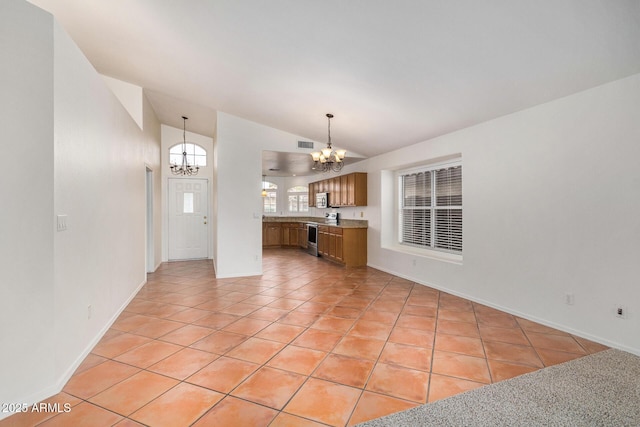 unfurnished living room with a notable chandelier, high vaulted ceiling, and light tile patterned flooring