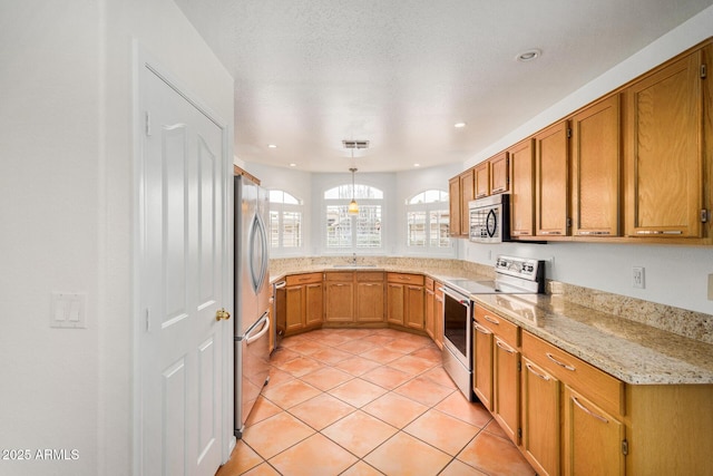 kitchen with sink, light stone counters, light tile patterned floors, appliances with stainless steel finishes, and pendant lighting