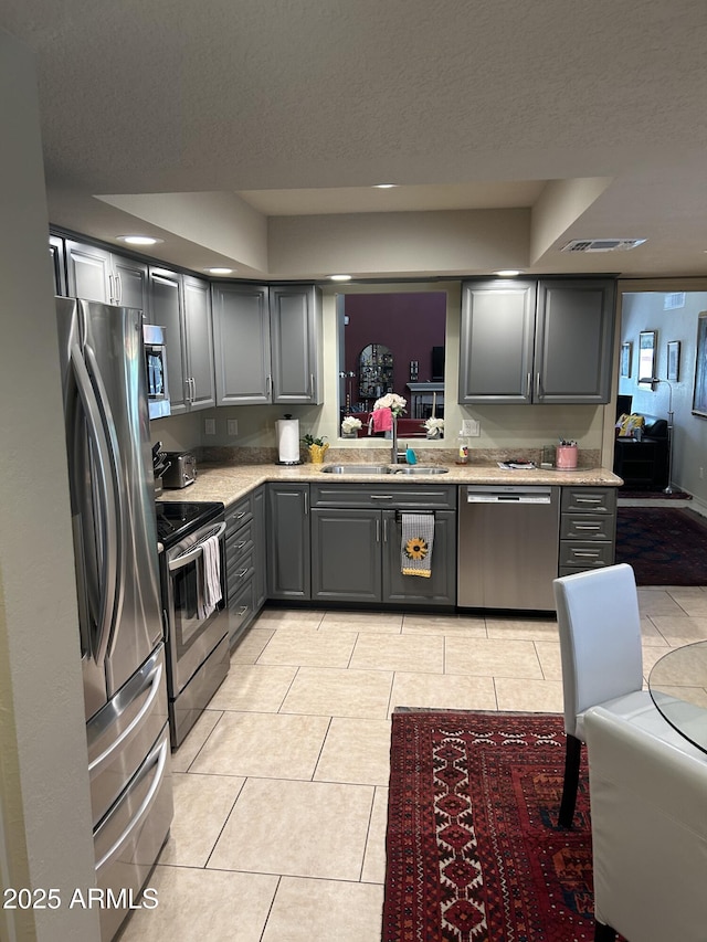 2413 E Rancho Dr, Phoenix, AZ 85016 - kitchen with appliances with stainless steel finishes, a sink, gray cabinetry, light tile patterned floors, and light stone counters