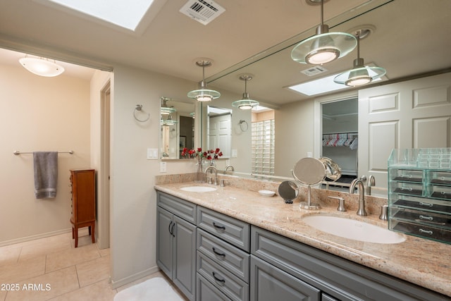2413 E Rancho Dr, Phoenix, AZ 85016 - bathroom featuring a skylight, double vanity, tile patterned flooring, and baseboards