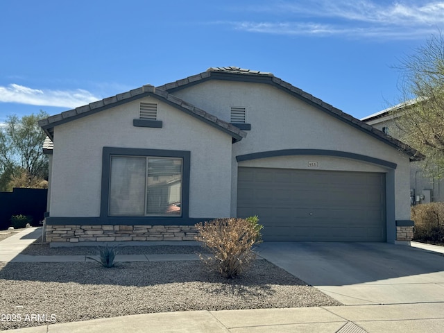 single story home with an attached garage, concrete driveway, stone siding, a tiled roof, and stucco siding