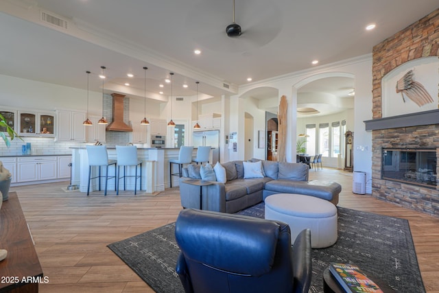 living room with ceiling fan, light hardwood / wood-style flooring, crown molding, and a fireplace