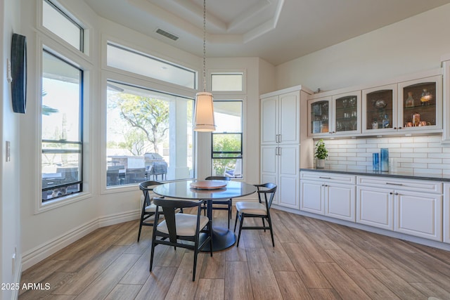 dining space with light hardwood / wood-style floors and a tray ceiling