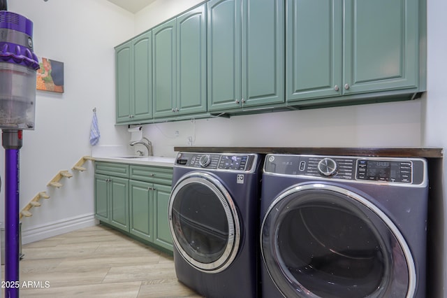 washroom with cabinets, light hardwood / wood-style floors, washer and clothes dryer, and sink