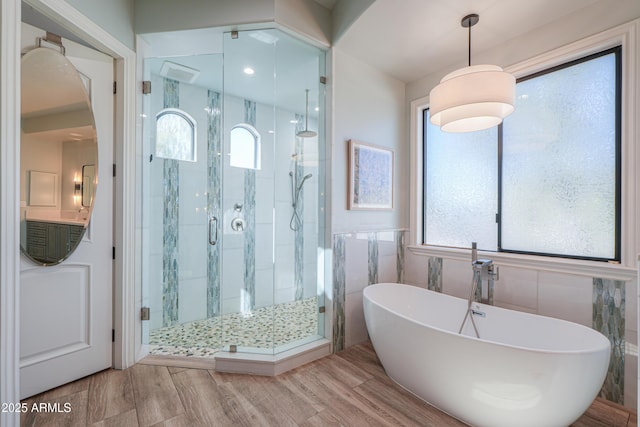 bathroom with tile walls and shower with separate bathtub