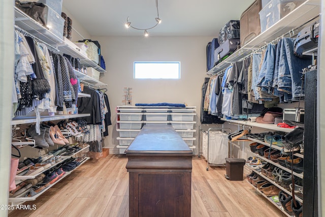 walk in closet with light hardwood / wood-style floors