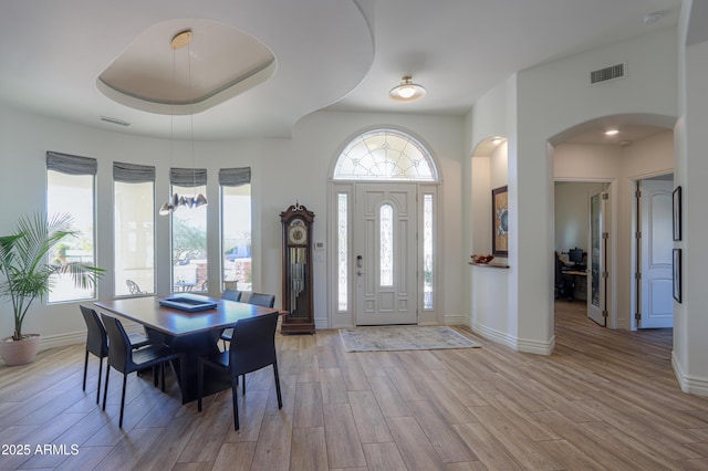 entrance foyer featuring light wood-type flooring, an inviting chandelier, and a raised ceiling