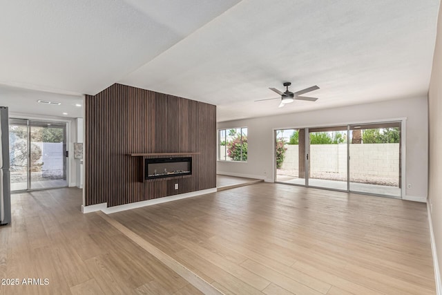 5526 N 77th Way, Scottsdale, AZ 85250 - unfurnished living room featuring ceiling fan, light wood-type flooring, a large fireplace, and baseboards