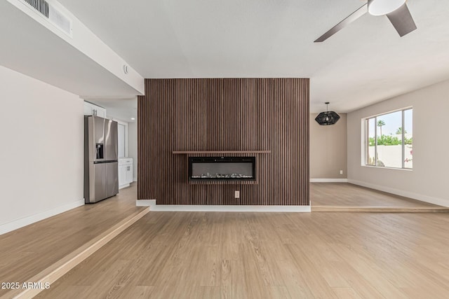 5526 N 77th Way, Scottsdale, AZ 85250 - unfurnished living room featuring ceiling fan, a fireplace, light wood-style flooring, and baseboards