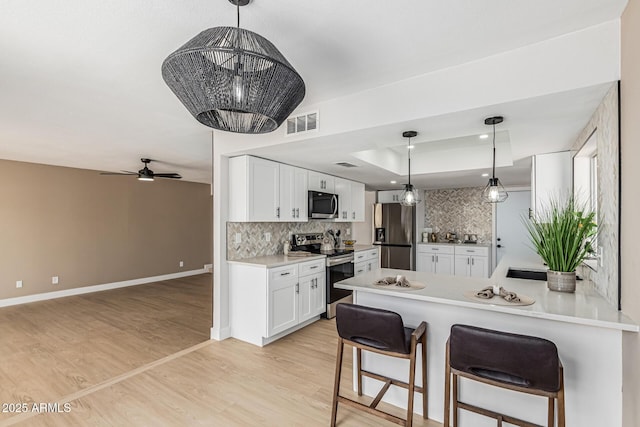 5526 N 77th Way, Scottsdale, AZ 85250 - kitchen with stainless steel appliances, decorative backsplash, white cabinetry, a peninsula, and a raised ceiling