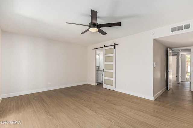 5526 N 77th Way, Scottsdale, AZ 85250 - unfurnished room with a ceiling fan, a barn door, wood finished floors, and baseboards