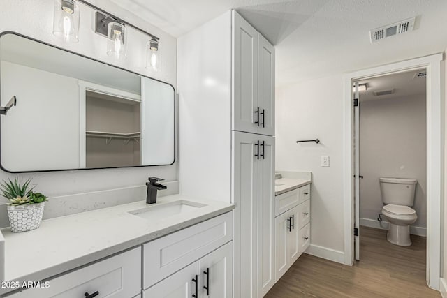 5526 N 77th Way, Scottsdale, AZ 85250 - bathroom featuring vanity, wood finished floors, baseboards, toilet, and a closet