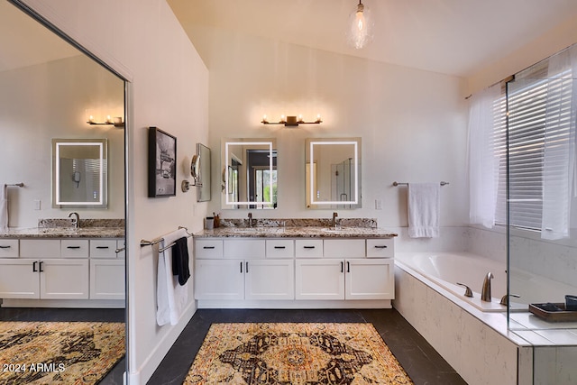 bathroom featuring tile patterned floors, vanity, vaulted ceiling, and tiled tub