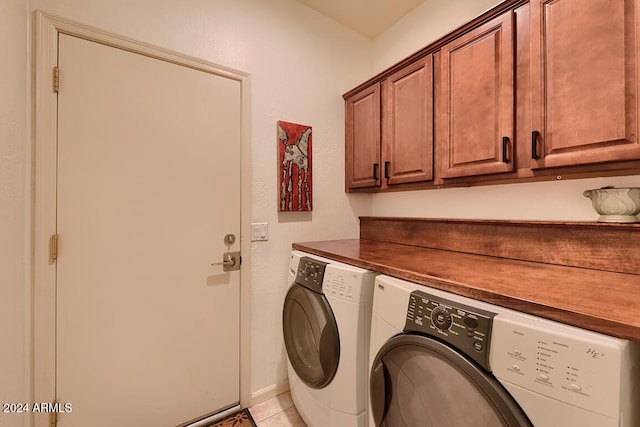 washroom with light tile patterned flooring, cabinets, and washing machine and dryer