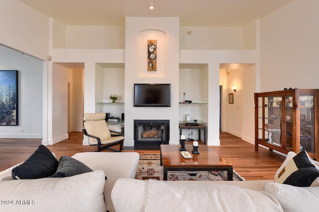 living room featuring built in shelves and wood-type flooring