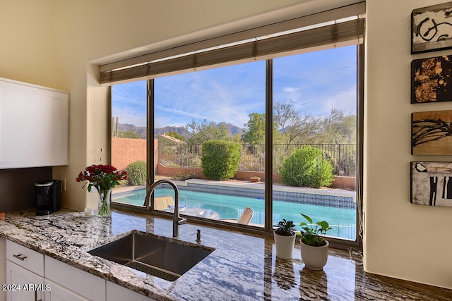 interior space featuring light stone countertops, a mountain view, dark wood-type flooring, sink, and white cabinets