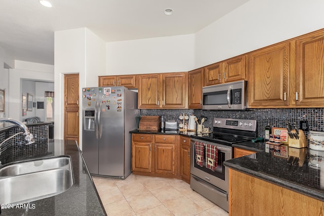 kitchen featuring backsplash, stainless steel appliances, dark stone counters, sink, and light tile floors