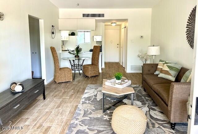living room featuring visible vents, baseboards, and wood finish floors