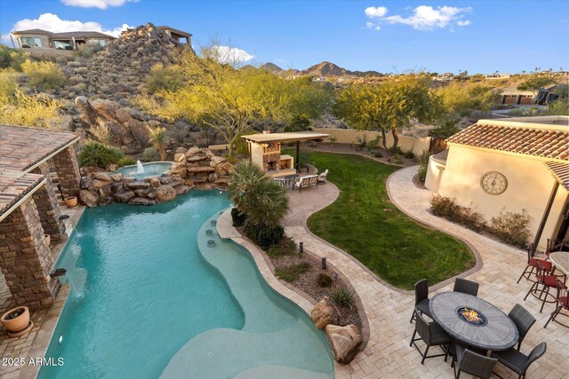 view of swimming pool featuring a lawn, a mountain view, an outdoor fireplace, pool water feature, and a patio area