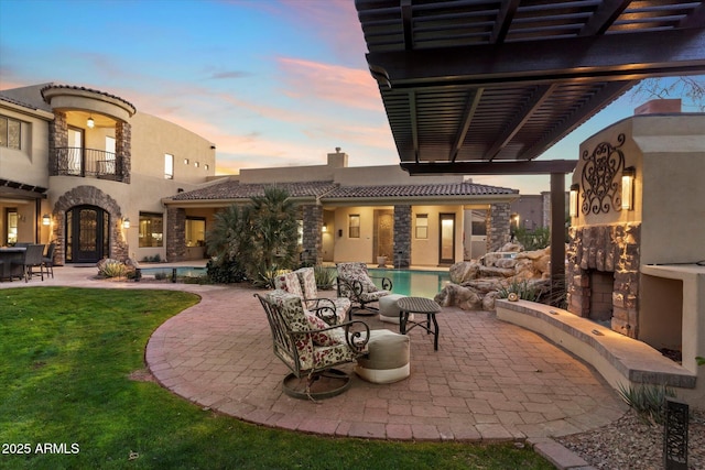 patio terrace at dusk featuring an outdoor hangout area, a balcony, and a pergola