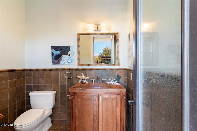 bathroom with walk in shower, vanity, toilet, and tile walls