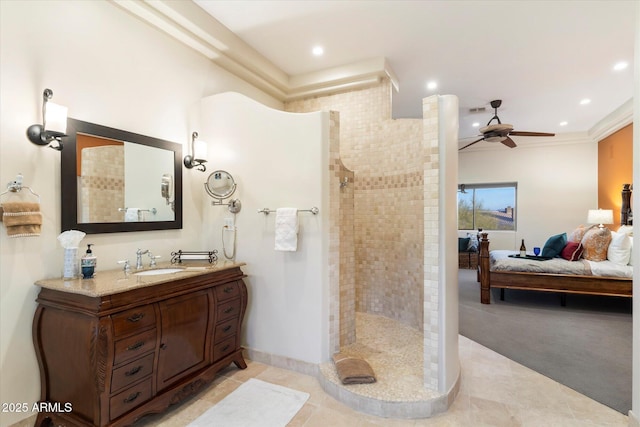 bathroom featuring a tile shower, ceiling fan, vanity, and ornamental molding