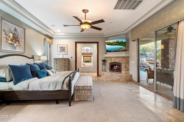 bedroom featuring ceiling fan, access to exterior, and a tray ceiling