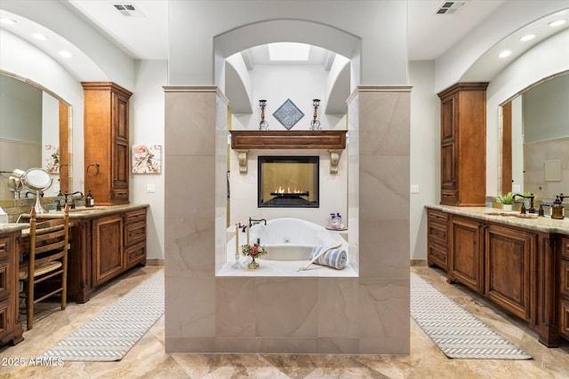 bathroom with a relaxing tiled tub and vanity