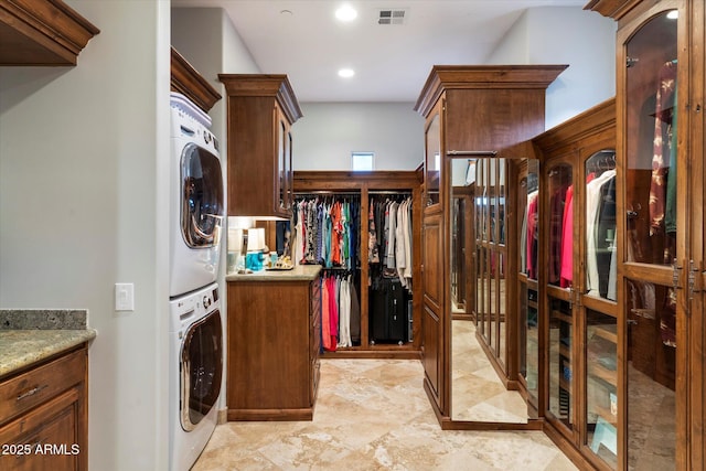 washroom with cabinets and stacked washer and clothes dryer