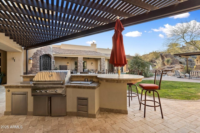 view of patio with a pergola, a grill, a bar, and an outdoor kitchen