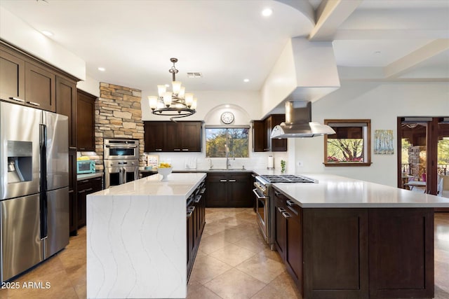 kitchen with appliances with stainless steel finishes, sink, exhaust hood, a center island, and hanging light fixtures