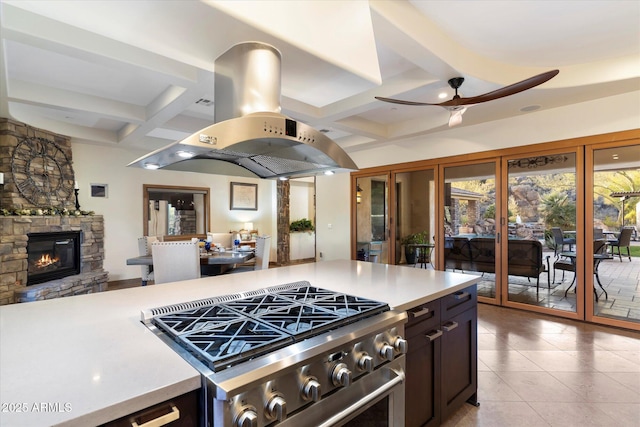 kitchen with island exhaust hood, coffered ceiling, high end stove, ceiling fan, and a fireplace