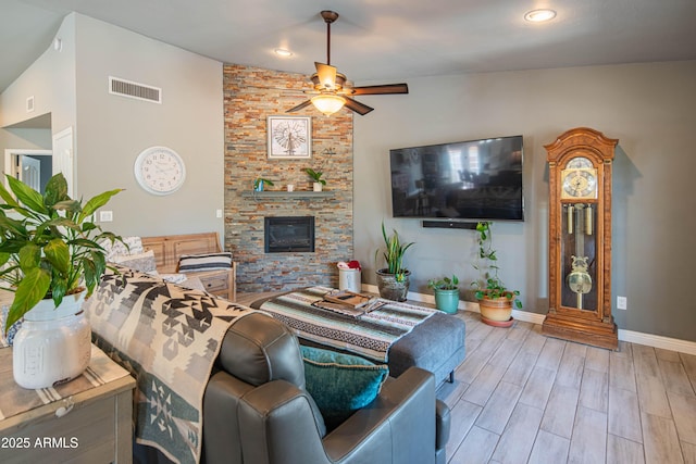 living room featuring wood finished floors, baseboards, visible vents, a fireplace, and ceiling fan