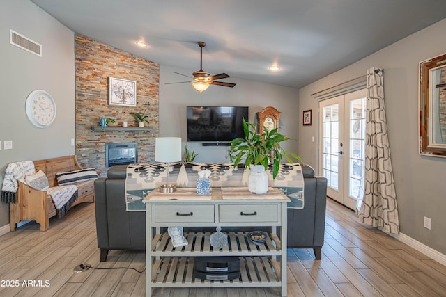 living area featuring wood finish floors, visible vents, french doors, and vaulted ceiling