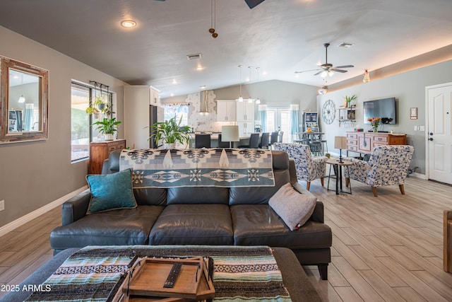 living area featuring a ceiling fan, visible vents, baseboards, lofted ceiling, and light wood-style floors