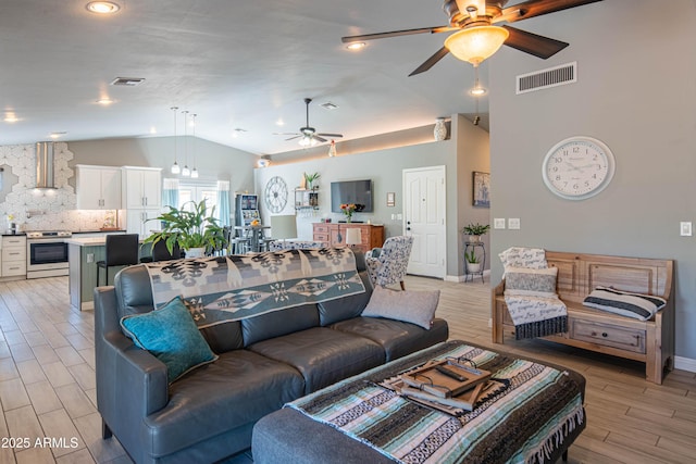 living room with baseboards, visible vents, lofted ceiling, ceiling fan, and light wood-type flooring