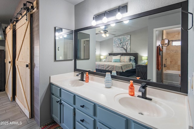 full bathroom with double vanity, connected bathroom, wood finish floors, and a sink